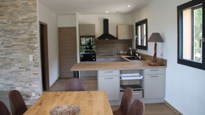 Una cucina moderna con un tavolo e sedie in legno, una parete decorata con pietra e vista sull'esterno attraverso una finestra.