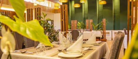 A restaurant with tables set for dining, featuring a modern interior with hanging lights and wooden accents.