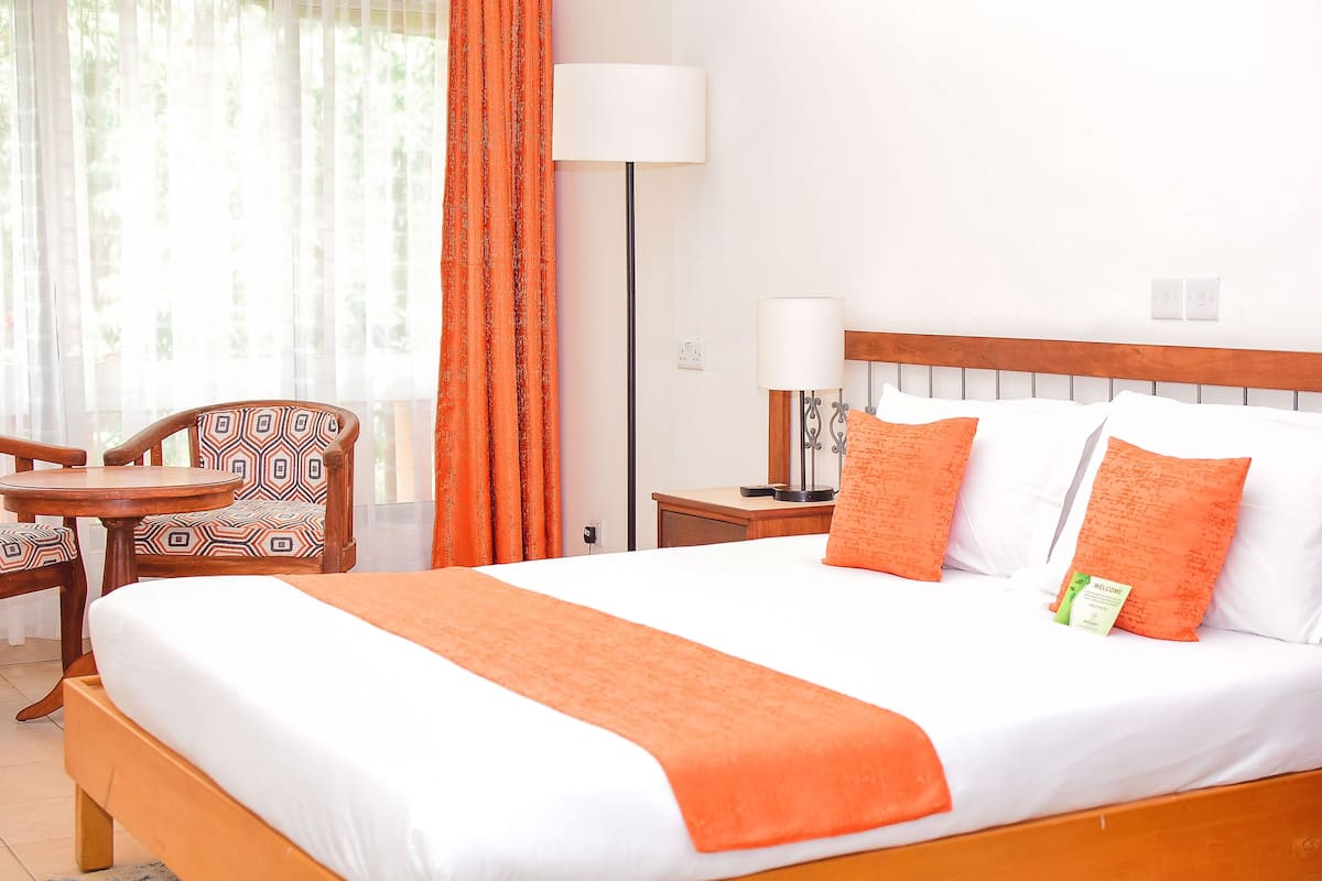 Une chambre d’hôtel avec un grand lit, une table de chevet, une chaise et une lampe.