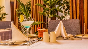 A dining table set with a martini glass, a cocktail, salt and pepper shakers, cutlery, and a napkin. - Hotel Boulevard Nairobi, City Centre CBD (Nairobi)