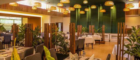 A restaurant with multiple tables set for dining, featuring a modern interior with wooden accents and hanging pendant lights.