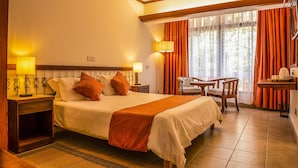 A hotel room with a large bed, two bedside lamps, a chair, a small table, and a window with curtains. - Hotel Boulevard Nairobi, City Centre CBD (Nairobi)