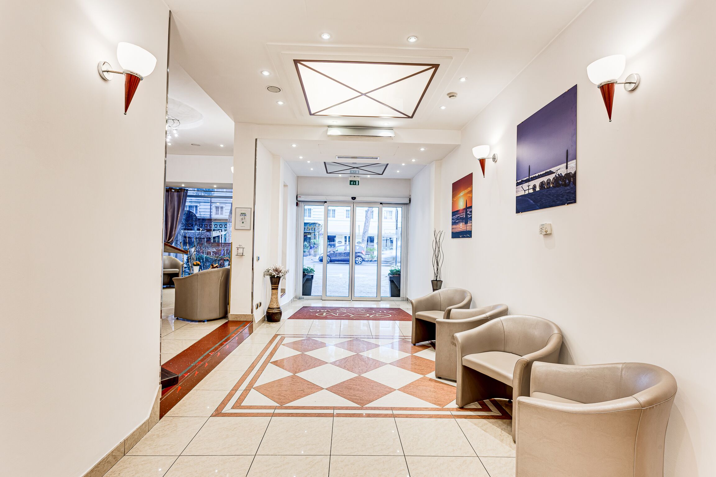 Vestíbulo de hotel con mostrador de recepción, zona de estar y piso estampado.