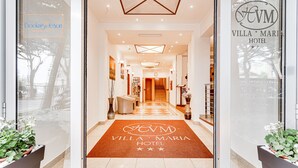 Entrada de un hotel con mostrador de recepción, una escalera y un pasillo que conduce a las habitaciones.