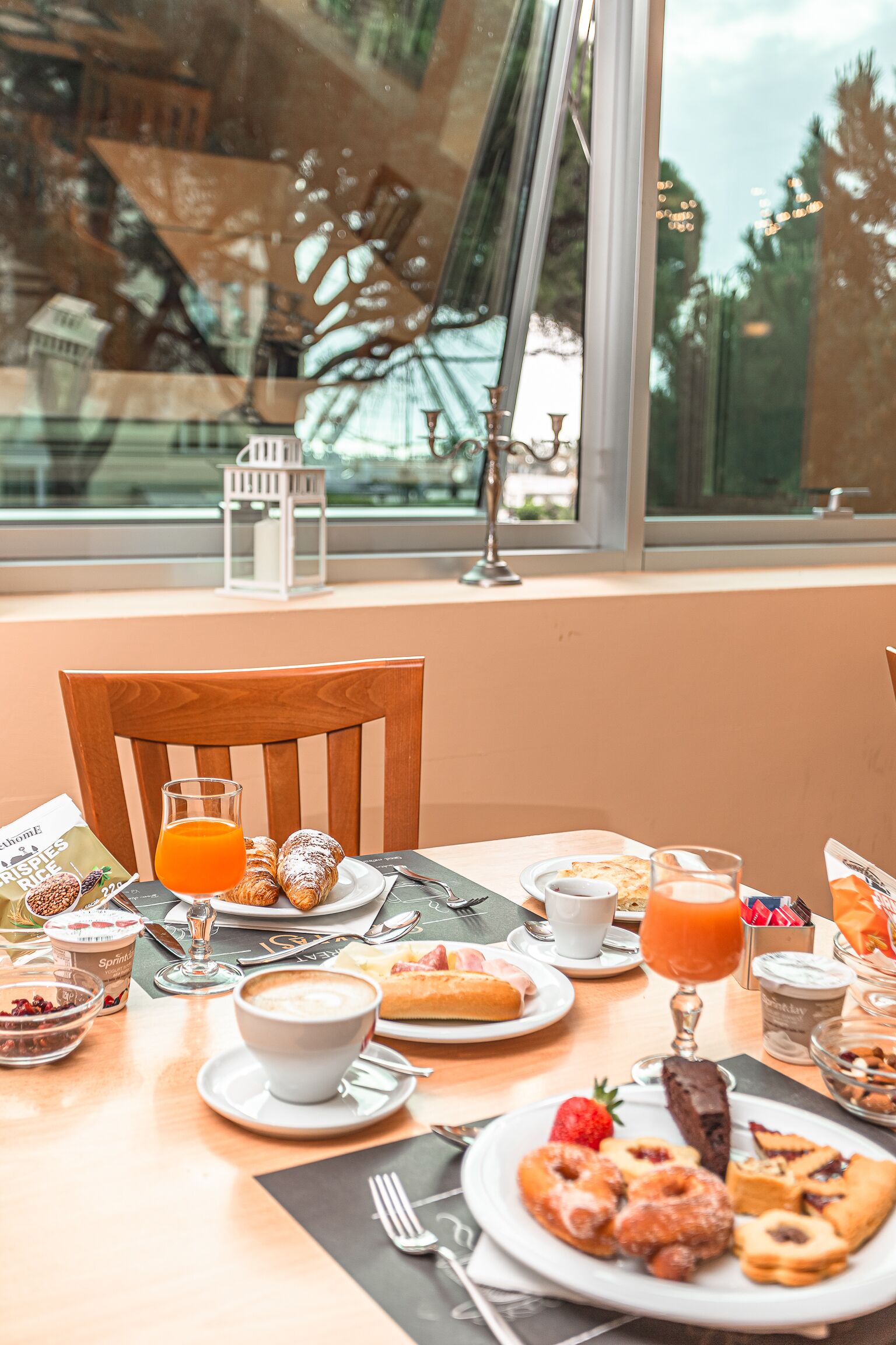 A breakfast table with pastries, a coffee cup, and a glass of orange juice.