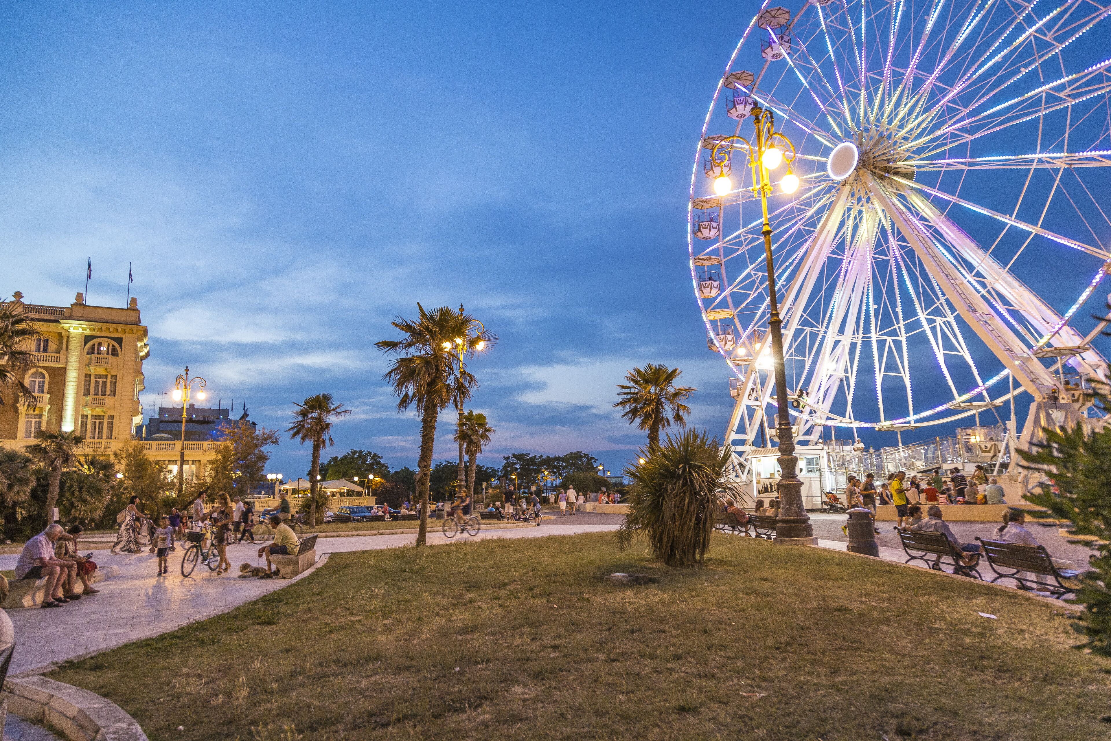 A Ferris wheel at dusk with people around.