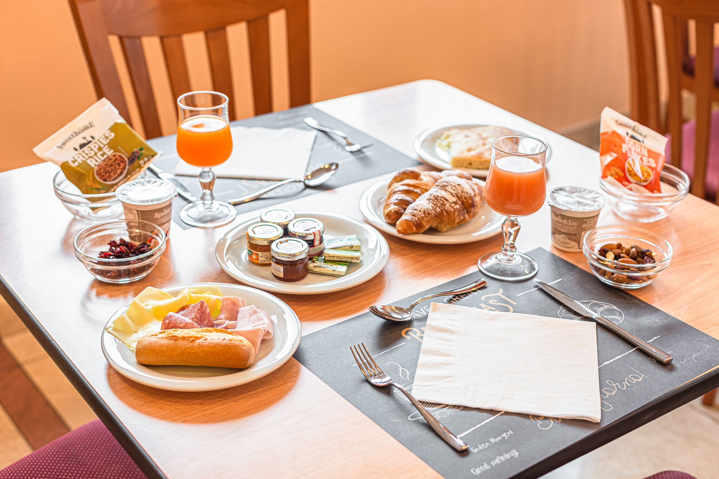 A breakfast table with croissants, fruit, and juice.