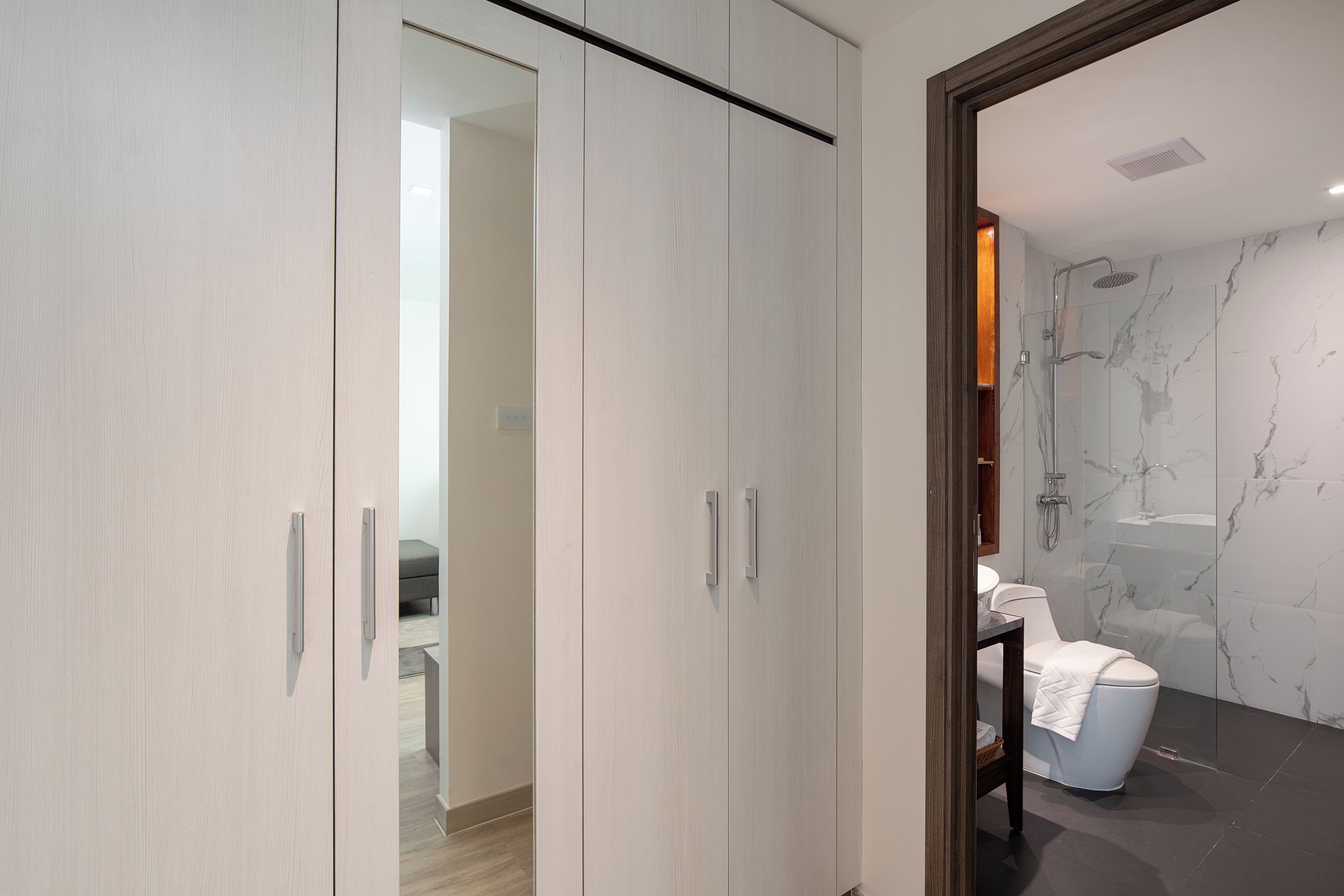 A modern bathroom with a glass shower enclosure, marble walls, and a white toilet.