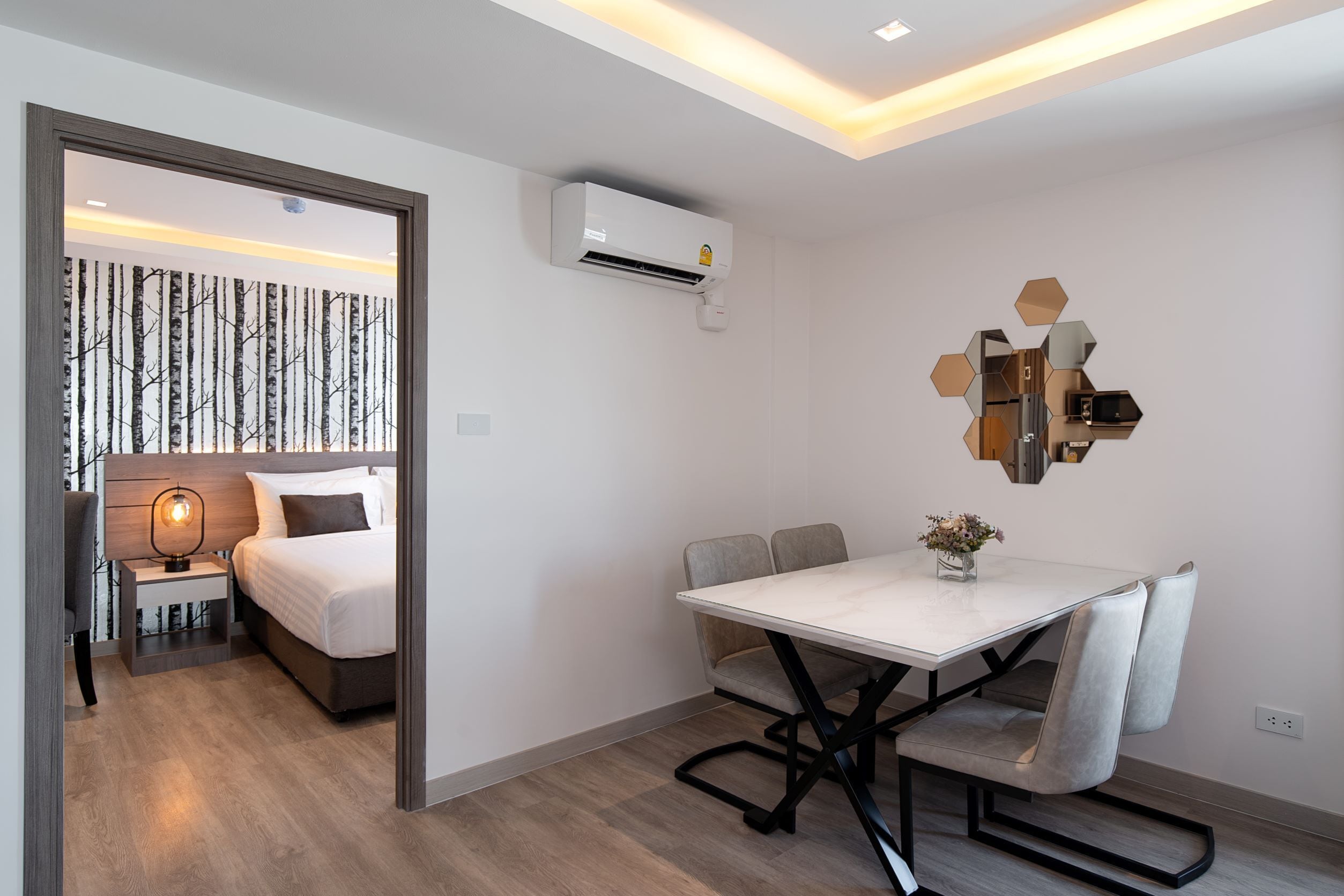 Une chambre d’hôtel moderne équipée d’un lit, d’une table de chevet, d’une lampe et d’un coin repas avec une table et des chaises.