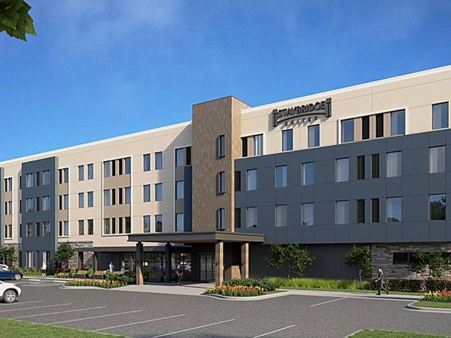 A modern hotel with a flat roof, multiple floors, and a central entrance.