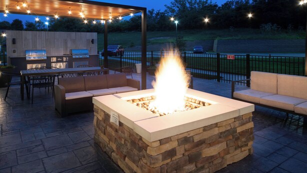 Une terrasse extérieure avec un foyer en pierre, un espace salon et un barbecue.
