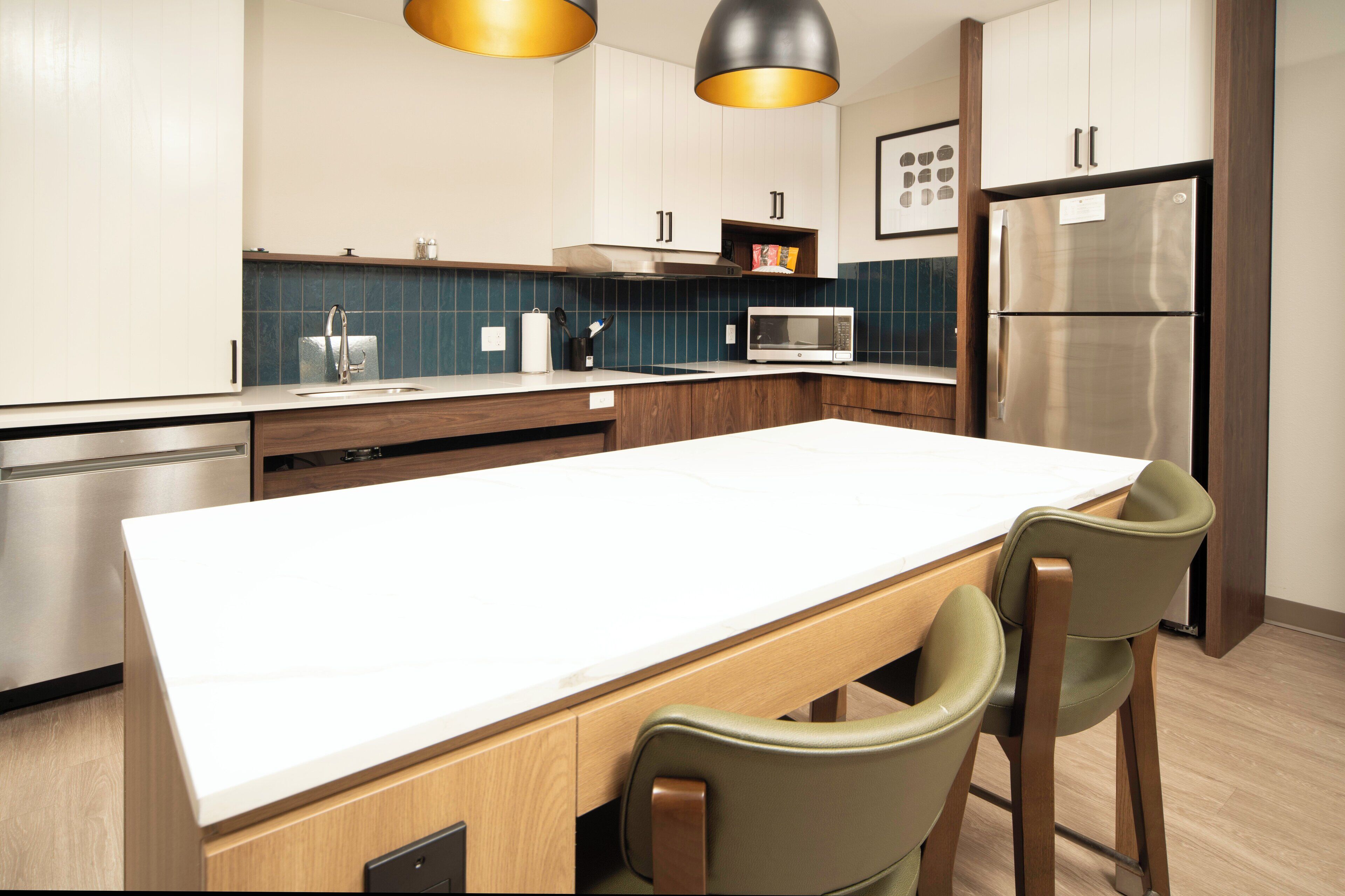 A modern kitchen with a central island, stainless steel appliances, and wooden cabinetry.