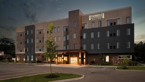 Un hôtel Staybridge Suites au design moderne, comprenant plusieurs étages et une entrée bien éclairée.