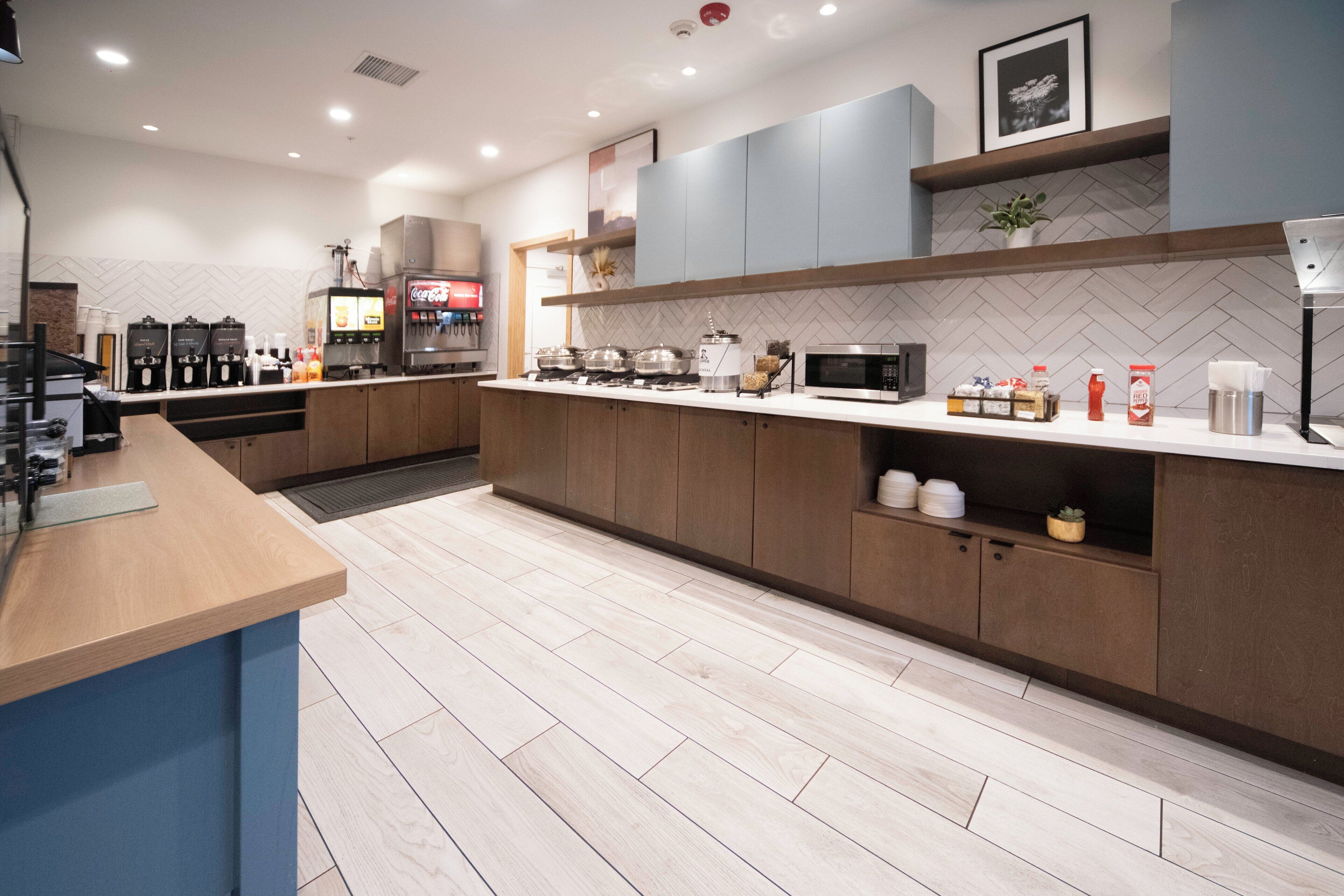 A modern kitchen with a wooden countertop, built-in appliances, and a herringbone tile backsplash.