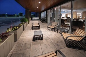 Un patio al aire libre con mobiliario y vistas al interior.