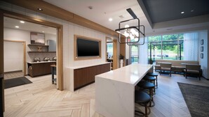 Une cuisine moderne dotée d’un grand îlot central, de meubles en bois et d’un téléviseur à écran plat.