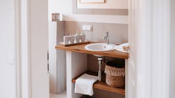 Ein modernes Badezimmer mit einem Holzkosmetikschrank, einem Waschbecken und einer kleinen Ablage für Toilettenartikel.
