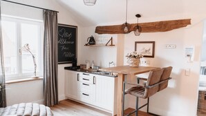 A modern kitchen with white cabinets, a wooden island, and a chalkboard with a welcome message.