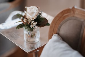 A clear view of a white rose in a glass vase on a wooden table. - Das Betthupferl - Ihr Aparthotel (Goldbach)