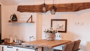 A modern kitchen with a wooden island, white cabinetry, and a rustic ceiling beam.