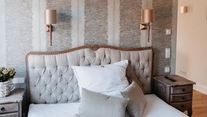 A bedroom with a tufted headboard, a bedside table with a lamp, and a nightstand with a remote control.