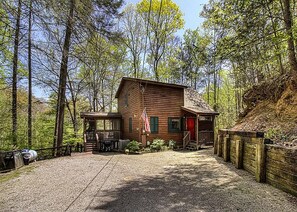 Een rustieke hut met een veranda, omgeven door een bos.