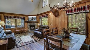 L’intérieur d’un chalet rustique, avec une cheminée en pierre, des meubles en cuir et un grand lustre orné de bois de cerf.