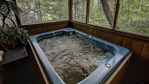 Un bain à remous dans un chalet en bois avec vue sur une forêt.