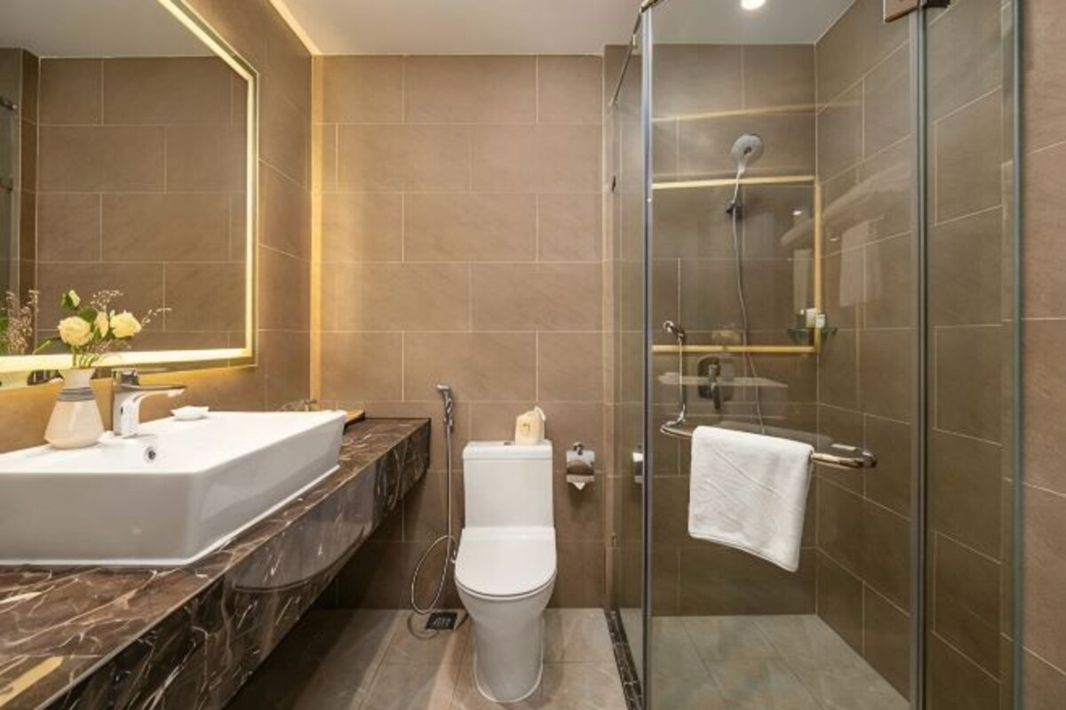 A bathroom with a glass-enclosed shower, a white sink, and a toilet.
