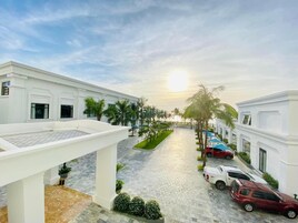 A white building with a covered walkway and parked cars.