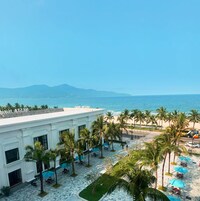 A hotel courtyard with palm trees, outdoor seating, and a view of the ocean.