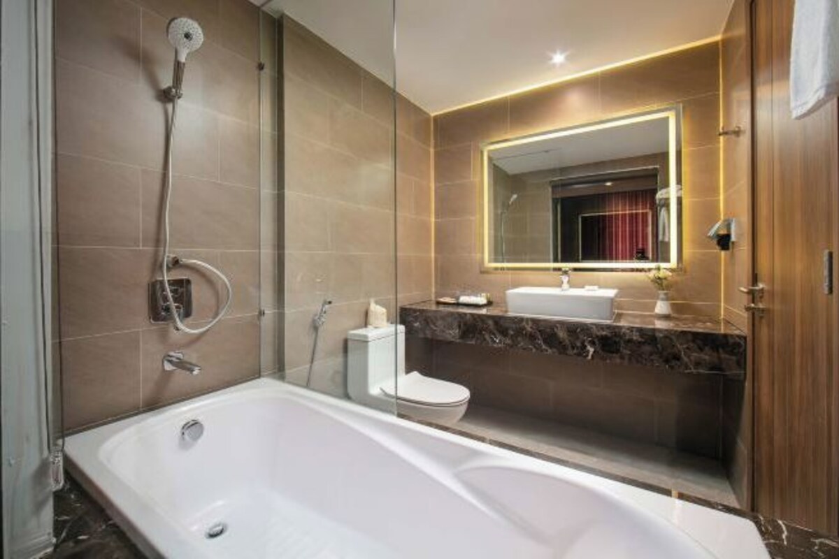 A modern bathroom with a large bathtub, a separate shower area, a vanity with a mirror, and a toilet.