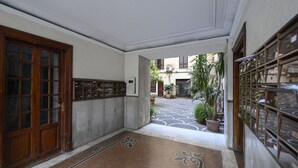 A hallway with a patterned floor, a wooden door, and a potted plant. - The Green House in Trastevere (Roma)
