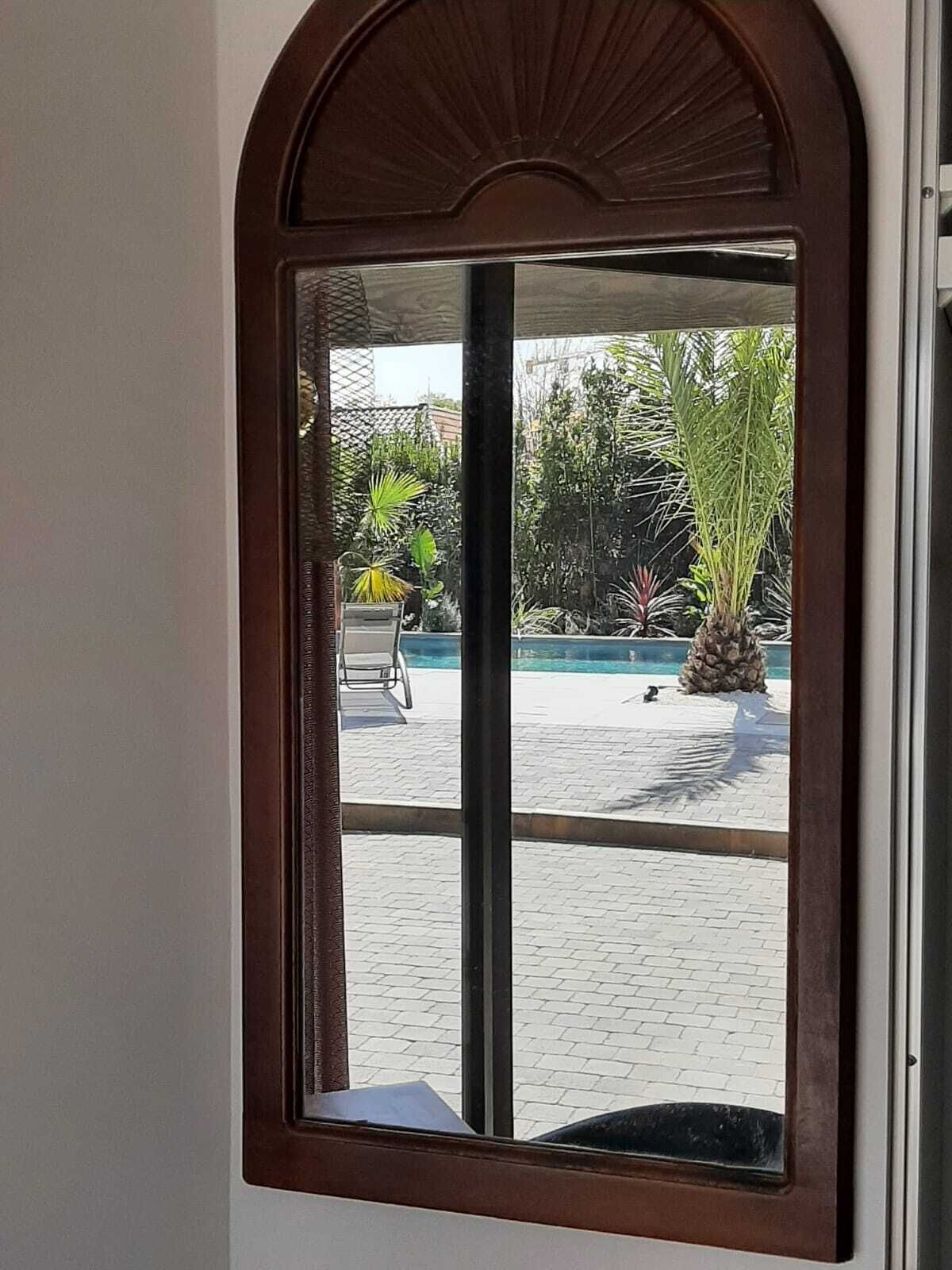 A window with a view of an outdoor area including a pool and plants.