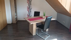 Un comedor con mesa de madera, una silla negra y un mantel individual rojo.