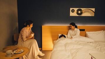 A hotel room with a bed, a bedside table with a cup and plate, and a wall art piece.
