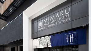 The exterior of the Mimaru Apartment Hotel Osaka Namba Station, featuring a modern facade with a prominent signage and a blue awning with a logo. - MIMARU Osaka Namba Station (Osaka)