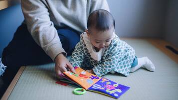 A person sitting on a tatami mat with a colorful book.