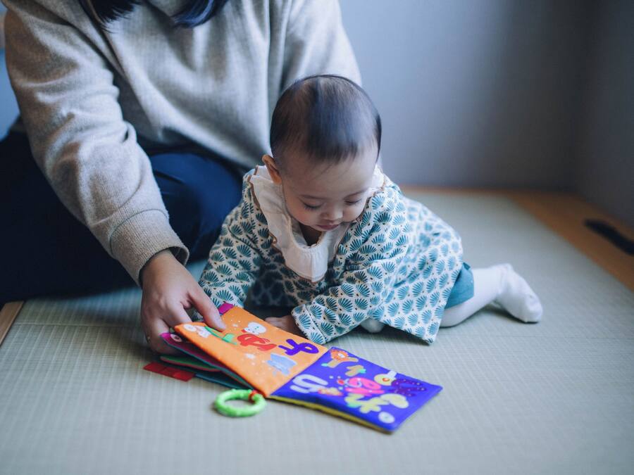 A person sitting on a tatami mat with a colorful book.