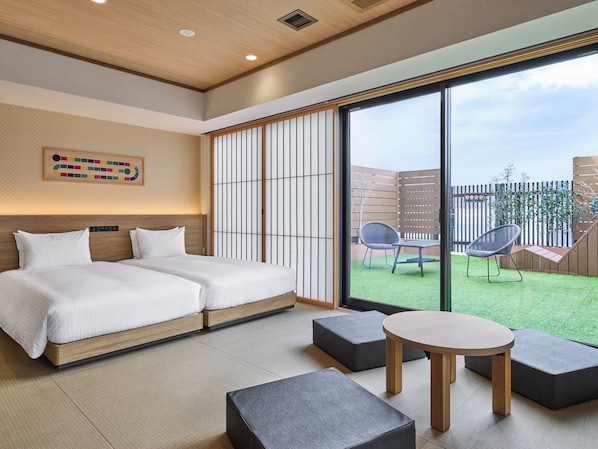 Una habitación de hotel moderna con un gran ventanal corredero que da a un jardín.