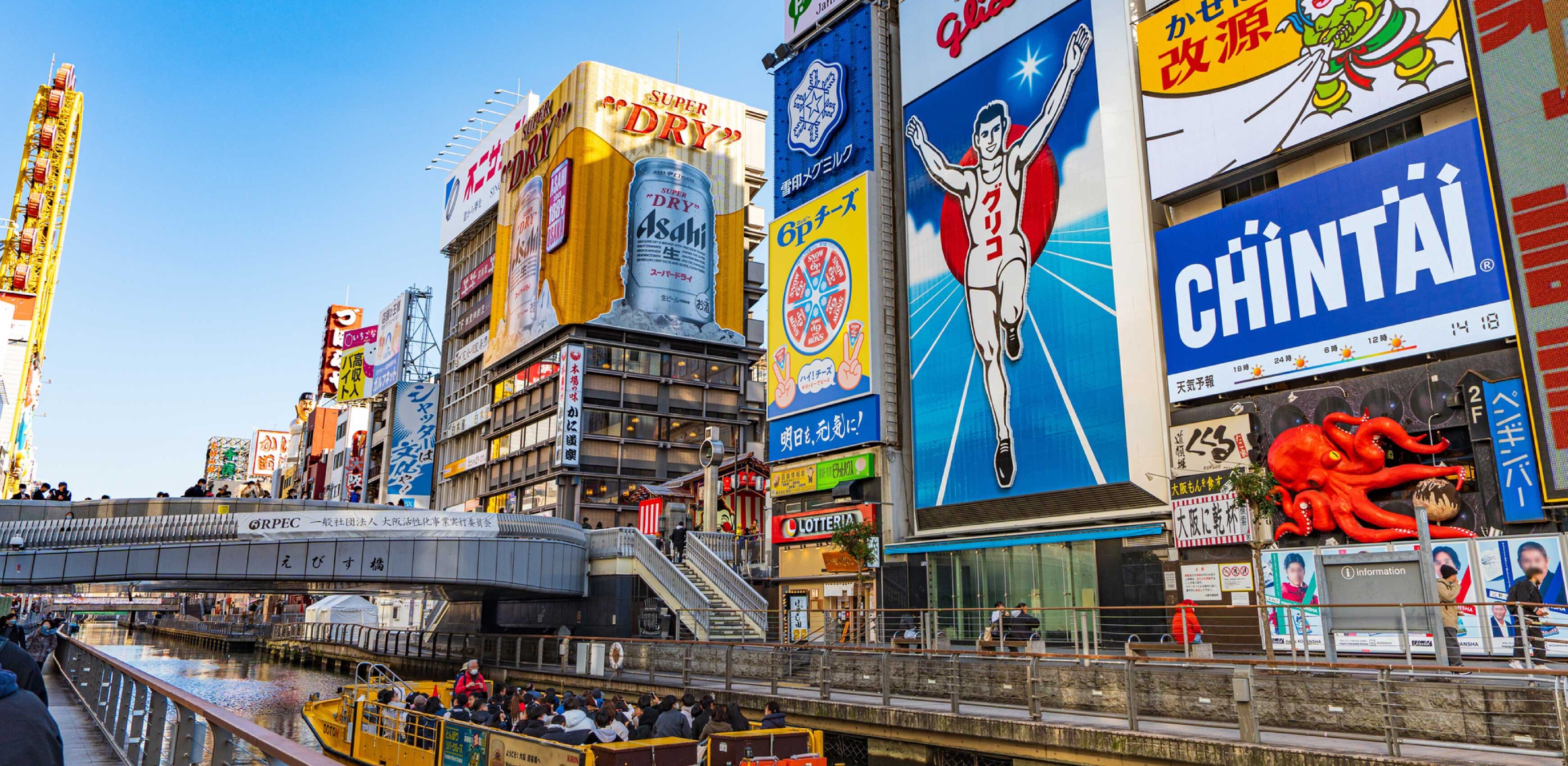 A busy urban street with various commercial buildings, including a prominent billboard for Asahi beer.