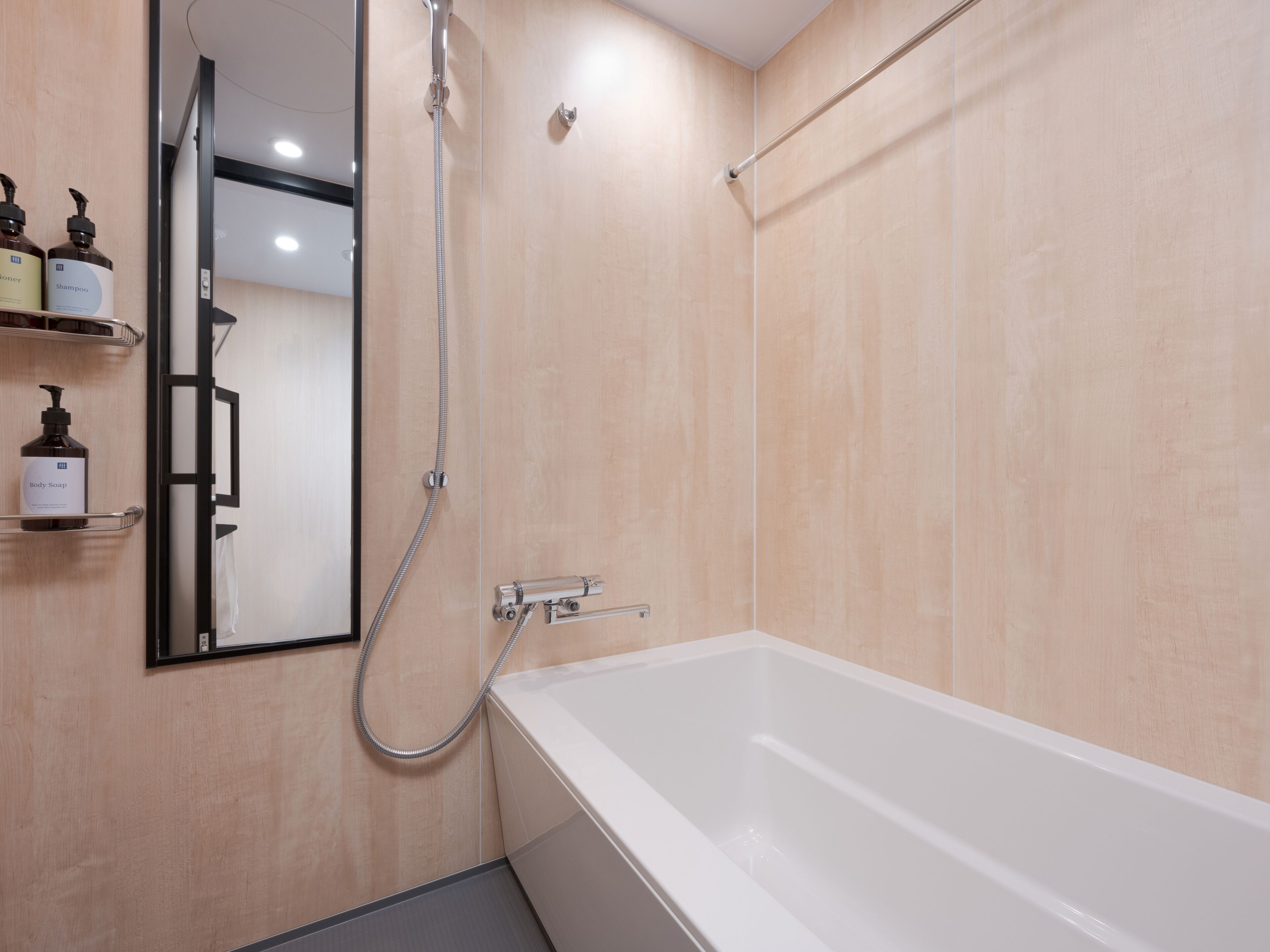 Une salle de bain moderne avec une baignoire blanche, une douchette à main et un miroir.