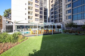 Um pátio com área de estar externa, piscina e espaço envidraçado.