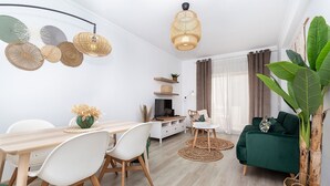 Una sala de estar moderna con comedor, un sofá verde y una planta grande.