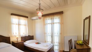 A hotel room with two beds, a chandelier, a radiator, and a chair. - FLORENA VILLAS (Lefkada)
