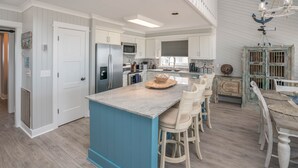 A spacious kitchen with a central island, white cabinetry, and a blue accent wall.