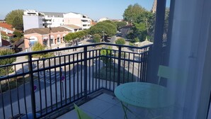 Een balkon met een metalen hekwerk, een tafeltje en stoelen.