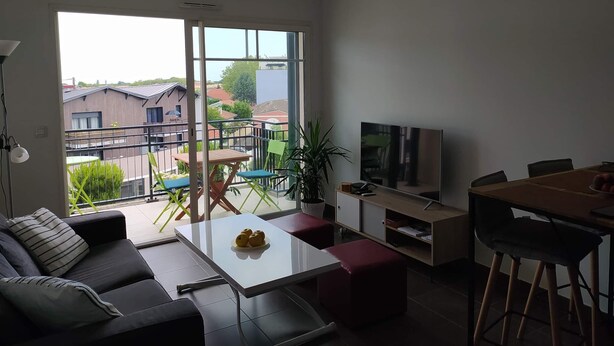 Een moderne woonkamer met een bank, een salontafel, een televisie en een balkon met uitzicht op de omgeving.