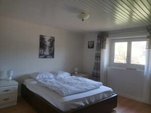Cozy retreat with a single bed, bedside table, and lamp, plus a window with a curtain and a framed picture on the wall.