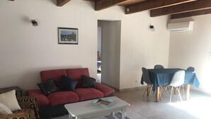 A living room with a red sofa, a white coffee table, and a dining area with a blue tablecloth. - Luberon: between Aix and Lourmarin (VILLELAURE)